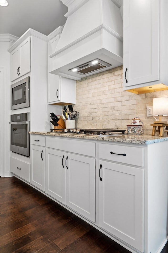 3983 Inlet Loop, Chattanooga, TN 37416 - kitchen featuring appliances with stainless steel finishes, custom range hood, light stone counters, dark wood-style floors, and white cabinets