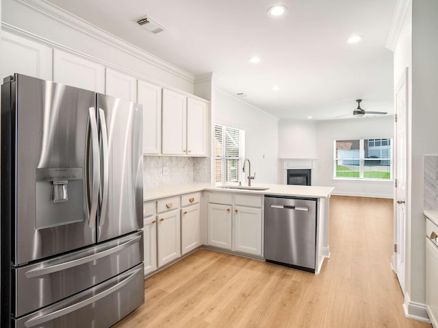 3038 Oxford Glen Dr, Franklin, TN 37067 - kitchen featuring appliances with stainless steel finishes, a sink, light wood-type flooring, a fireplace, and recessed lighting