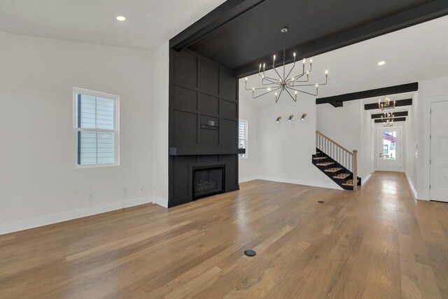5735 Willoughby Way, Murfreesboro, TN 37129 - unfurnished living room with a chandelier, stairway, a fireplace, light wood-style flooring, and beam ceiling