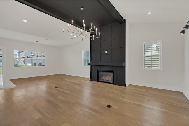 5735 Willoughby Way, Murfreesboro, TN 37129 - unfurnished living room featuring a chandelier, healthy amount of natural light, baseboards, light wood-style flooring, and lofted ceiling