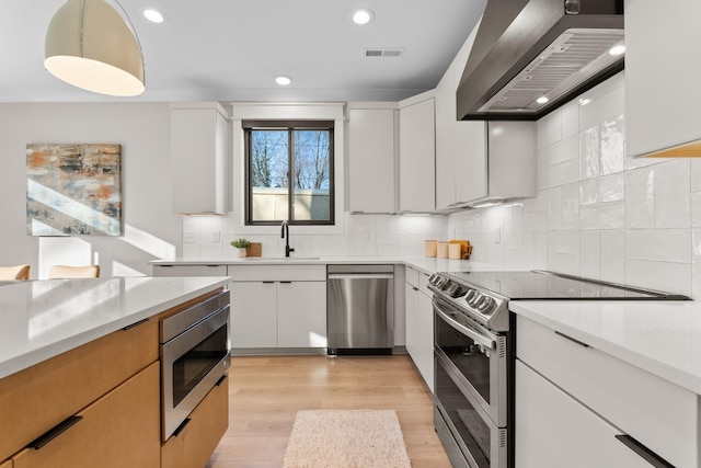 725 N Highland Ave, Murfreesboro, TN 37130 - kitchen with stainless steel appliances, wall chimney range hood, a sink, light wood finished floors, and light countertops