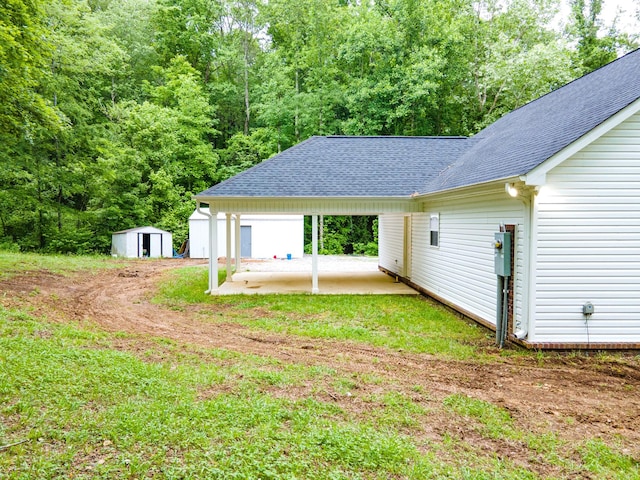 101 Henry Thompson Rd, Taft, TN 38488 - rear view of house with roof with shingles, a patio area, an outdoor structure, a storage unit, and driveway