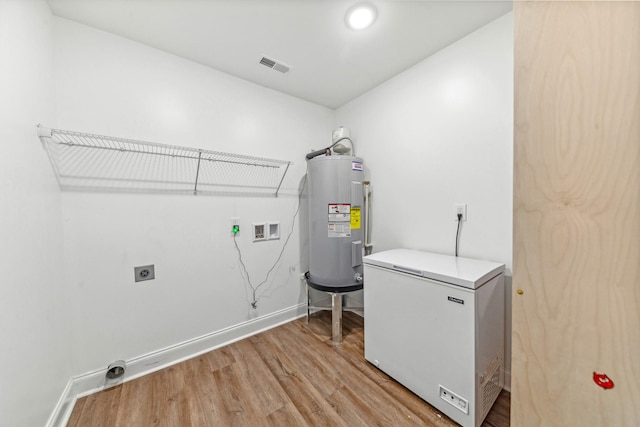 101 Henry Thompson Rd, Taft, TN 38488 - laundry room featuring electric water heater, hookup for a washing machine, hookup for an electric dryer, light wood-type flooring, and baseboards
