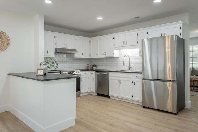 9039 Dallas Hollow Rd, Soddy Daisy, TN 37379 - kitchen featuring stainless steel appliances, under cabinet range hood, dark countertops, a sink, and white cabinetry