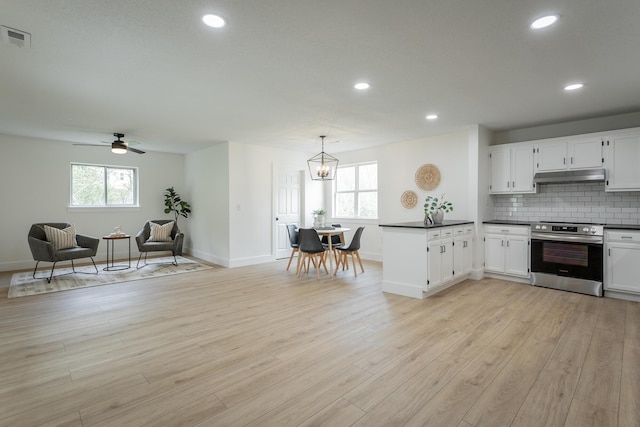 9039 Dallas Hollow Rd, Soddy Daisy, TN 37379 - kitchen with stainless steel electric range, under cabinet range hood, dark countertops, baseboards, and white cabinetry