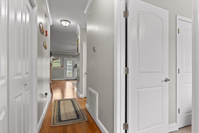 hallway featuring crown molding, wood finished floors, and baseboards
