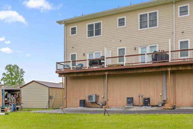 back of house with a lawn, a storage shed, an outbuilding, and cooling unit