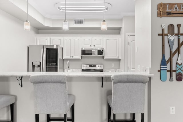 kitchen featuring appliances with stainless steel finishes, a breakfast bar, white cabinets, and ornamental molding