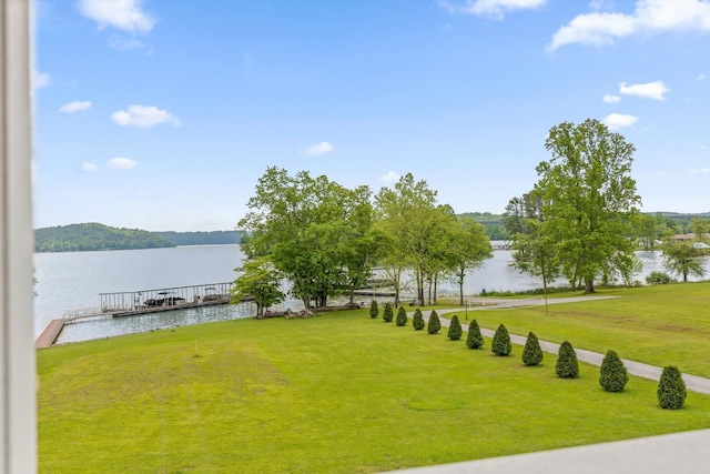 view of green lawn with a water view and a dock