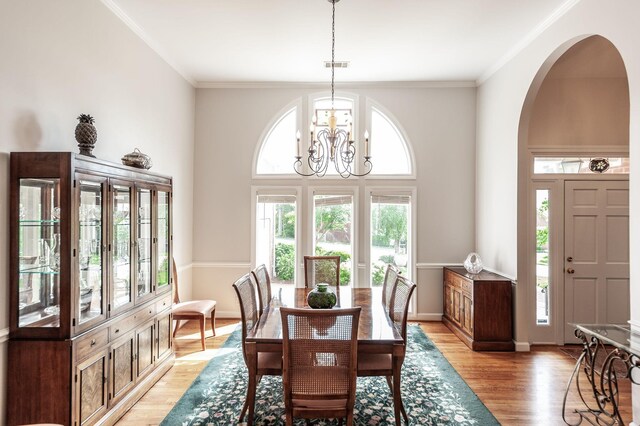 6737 Autumnwood Dr, Nashville, TN 37221 - dining room with light wood-style flooring, a chandelier, arched walkways, crown molding, and a towering ceiling