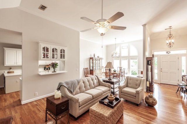 6737 Autumnwood Dr, Nashville, TN 37221 - living room featuring a chandelier, light wood-style floors, a ceiling fan, a towering ceiling, and ornamental molding