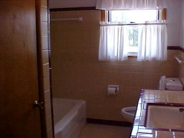 full bath with tile walls, toilet, a shower, and a bath