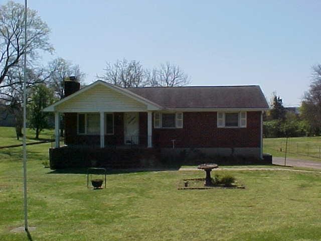 view of front facade with covered porch, a front lawn, a chimney, and brick siding