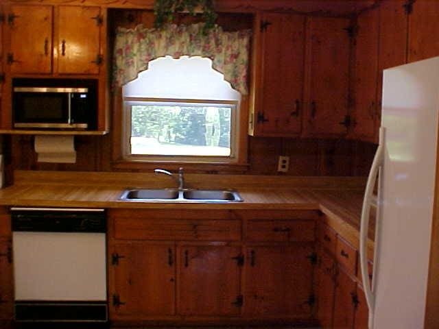 kitchen with white appliances, a sink, light countertops, and brown cabinets