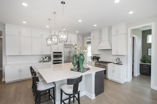 5969 Hunt Valley Dr, Spring Hill, TN 37174 - kitchen featuring high end appliances, custom range hood, decorative backsplash, a center island, and white cabinets