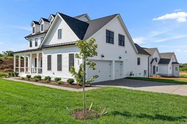 1941 Harmony Rd, Spring Hill, TN 37174 - view of side of home with a garage, asphalt driveway, a yard, a standing seam roof, and metal roof