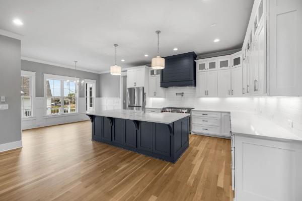 1941 Harmony Rd, Spring Hill, TN 37174 - kitchen with freestanding refrigerator, premium range hood, ornamental molding, white cabinets, and light countertops