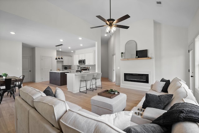 178 Dewberry Ct, Clarksville, TN 37042 - living area featuring light wood-type flooring, recessed lighting, a ceiling fan, a glass covered fireplace, and high vaulted ceiling