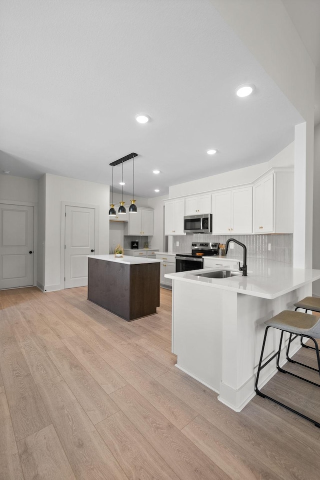 178 Dewberry Ct, Clarksville, TN 37042 - kitchen with stainless steel appliances, a sink, light wood finished floors, white cabinetry, and a peninsula