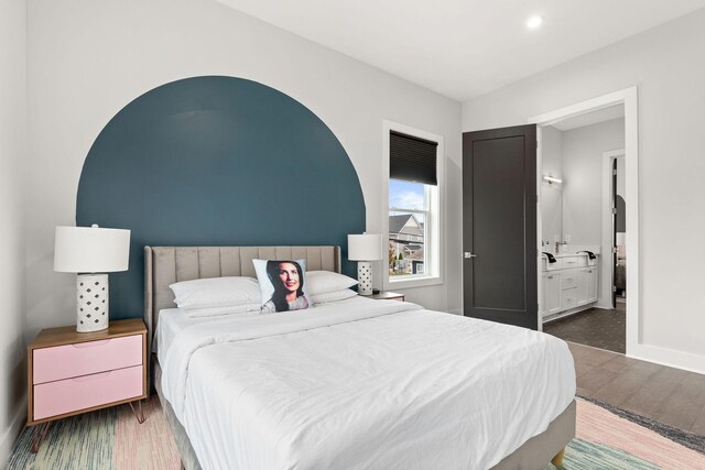 bedroom featuring wood finished floors, baseboards, ensuite bathroom, and recessed lighting