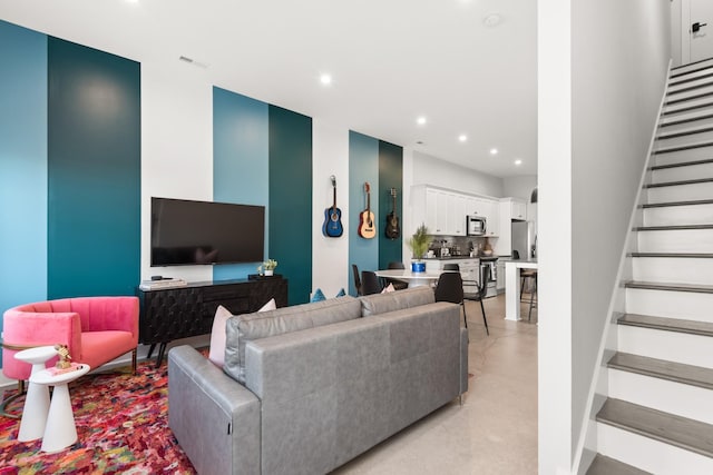 living room featuring stairs, recessed lighting, concrete flooring, and a high ceiling