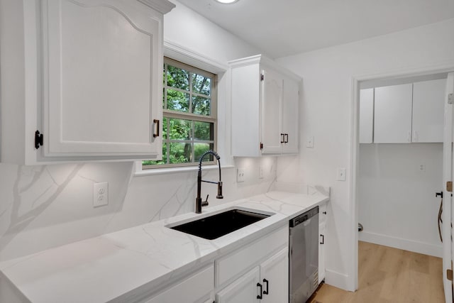 kitchen with dishwasher, a sink, light stone countertops, light wood-type flooring, and white cabinets