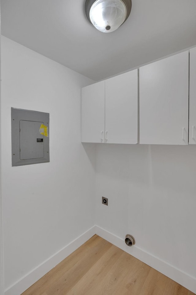 laundry area with electric panel, hookup for an electric dryer, light wood-style flooring, cabinet space, and baseboards