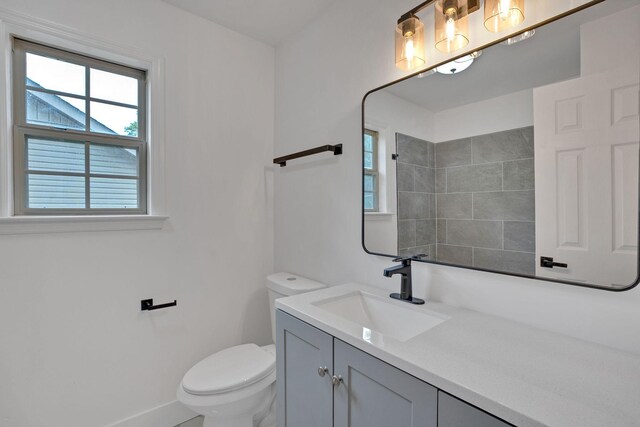full bathroom with baseboards, toilet, vanity, and a shower