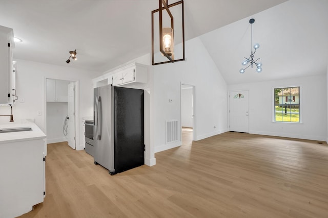 kitchen featuring stainless steel appliances, a sink, light wood-style flooring, white cabinets, and baseboards