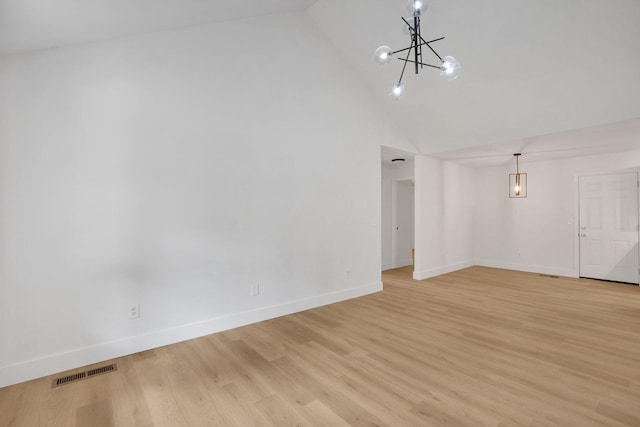 unfurnished living room featuring a chandelier, baseboards, light wood-style floors, and high vaulted ceiling