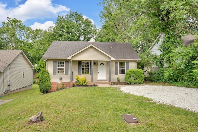 view of front of home featuring roof with shingles, a porch, a front yard, and driveway