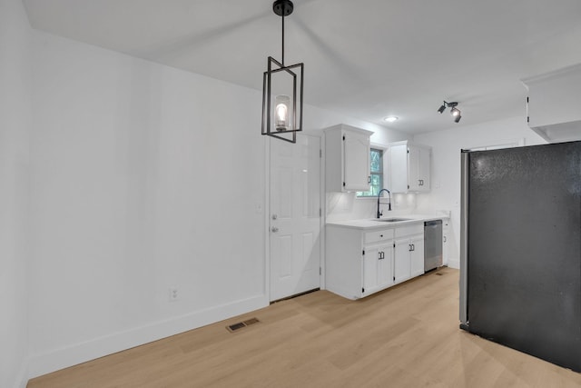 kitchen featuring appliances with stainless steel finishes, a sink, light countertops, light wood-style flooring, and white cabinetry