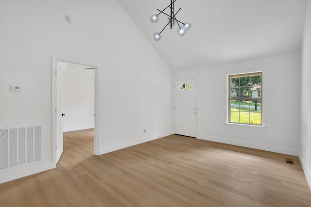 unfurnished living room featuring high vaulted ceiling, a chandelier, light wood-type flooring, and baseboards