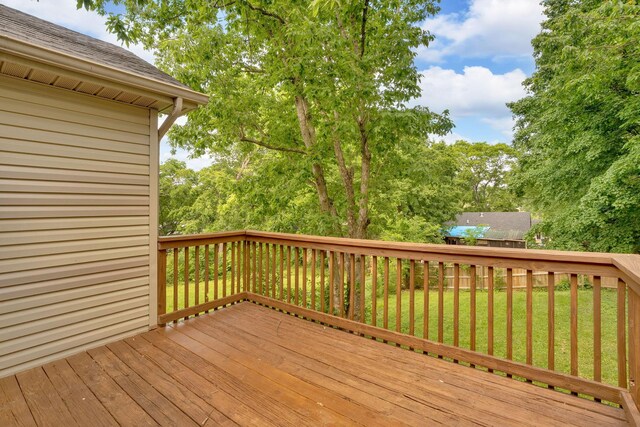 wooden terrace featuring a lawn and view of scattered trees
