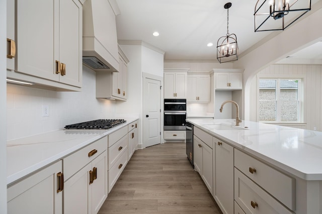 508 Gresham Ln, Murfreesboro, TN 37129 - kitchen featuring a sink, a chandelier, stainless steel appliances, light wood finished floors, and decorative backsplash
