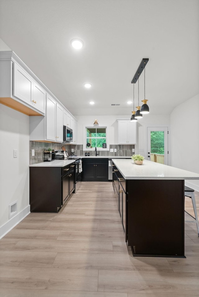182 Dewberry Ct, Clarksville, TN 37042 - kitchen featuring appliances with stainless steel finishes, white cabinets, light countertops, a kitchen island, and light wood-type flooring