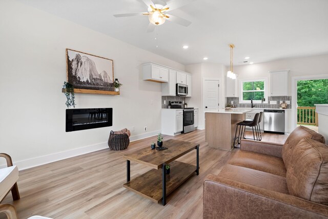 186 Dewberry Ct, Clarksville, TN 37042 - living area featuring light wood-type flooring, a ceiling fan, a glass covered fireplace, recessed lighting, and baseboards