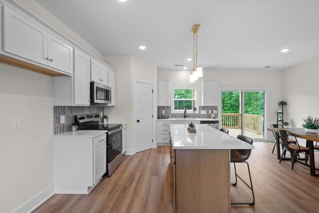 186 Dewberry Ct, Clarksville, TN 37042 - kitchen featuring appliances with stainless steel finishes, backsplash, a center island, a kitchen breakfast bar, and light wood-style floors