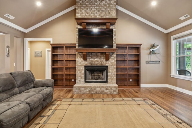 living area featuring lofted ceiling, wood finished floors, baseboards, a brick fireplace, and crown molding