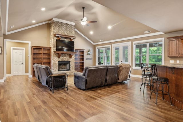 living room with ceiling fan, a brick fireplace, light wood-type flooring, baseboards, and vaulted ceiling