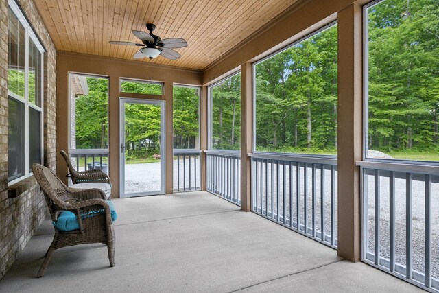 unfurnished sunroom featuring ceiling fan and view of scattered trees
