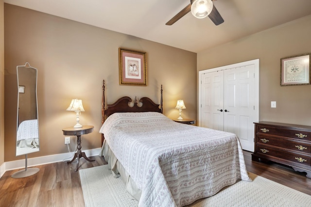 bedroom with a closet, wood finished floors, baseboards, and a ceiling fan