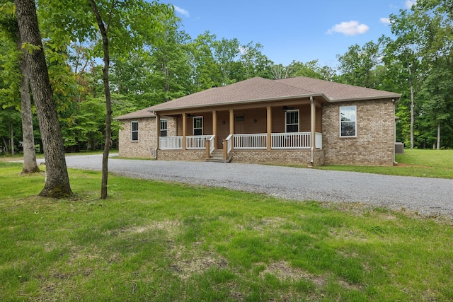 single story home with a porch, curved driveway, a front yard, and brick siding