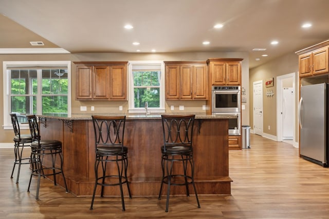 kitchen featuring appliances with stainless steel finishes, light wood-style flooring, recessed lighting, baseboards, and a breakfast bar