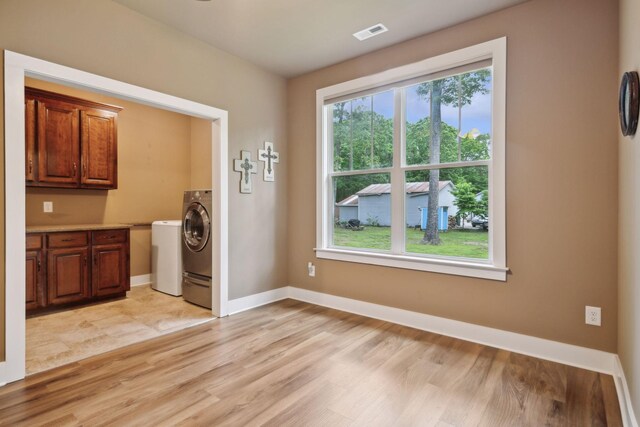 unfurnished dining area with light wood-style flooring, washer / clothes dryer, and baseboards