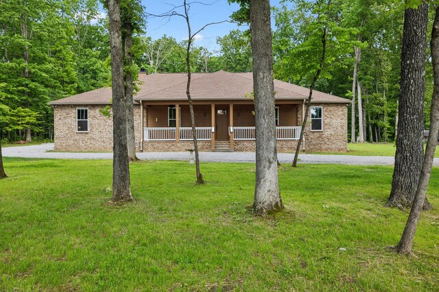 ranch-style home with a porch, a front yard, a shingled roof, and brick siding