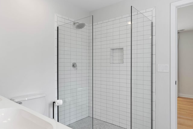 full bath with a stall shower, toilet, and wood finished floors