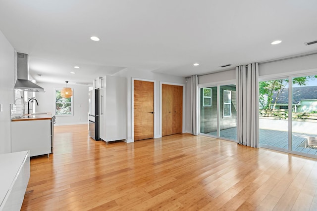 unfurnished living room featuring light wood-style flooring, recessed lighting, and a sink