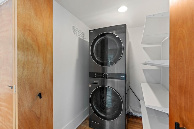 clothes washing area with stacked washer / dryer and wood finished floors