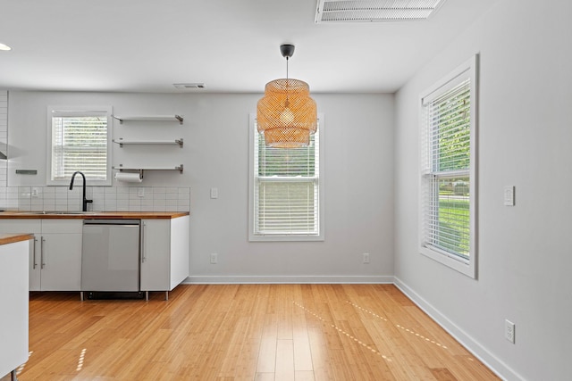 kitchen featuring a sink, stainless steel dishwasher, light wood-type flooring, and white cabinets